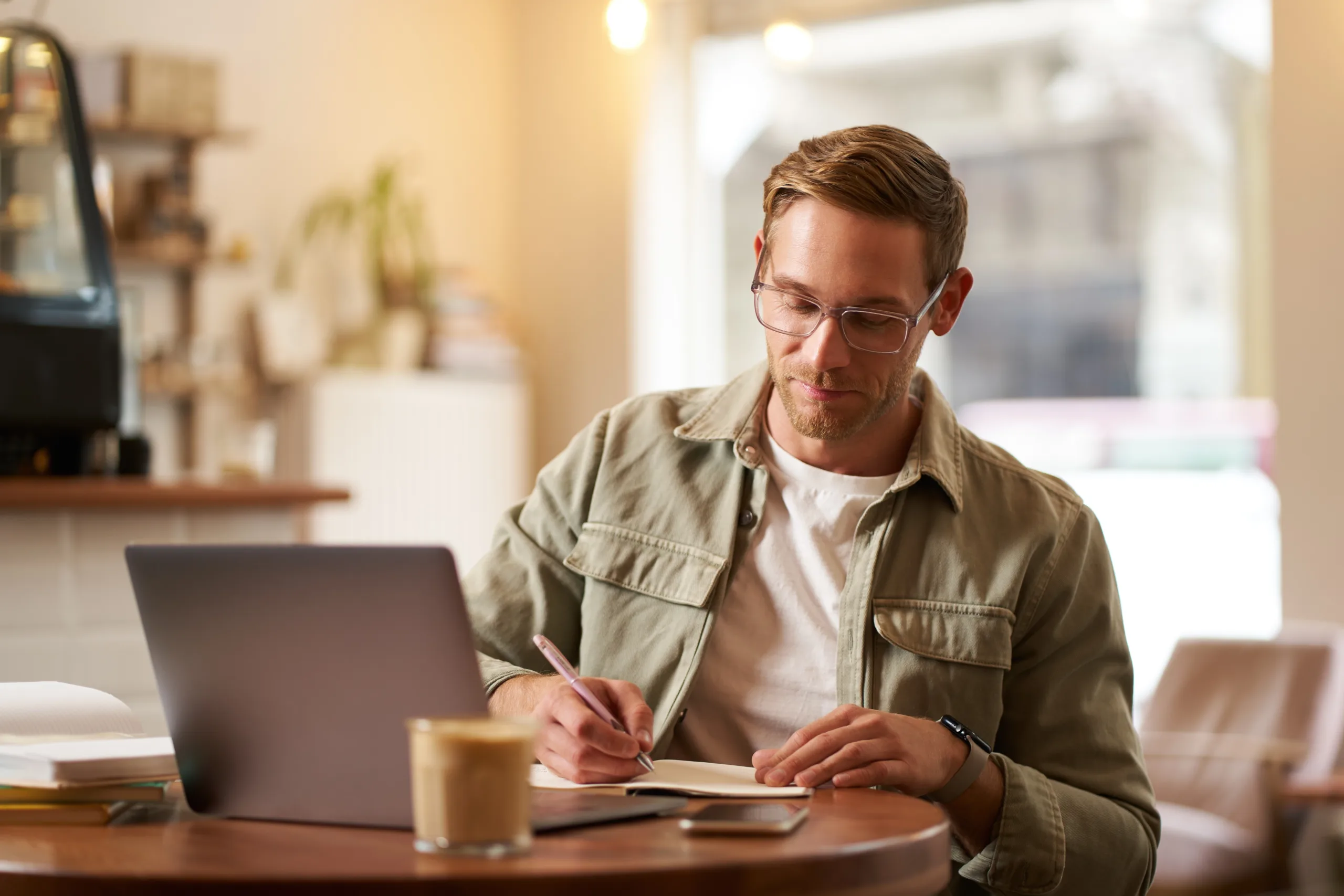 portrait handsome young guy glasses man studying taking notes looking laptop screen 1 scaled